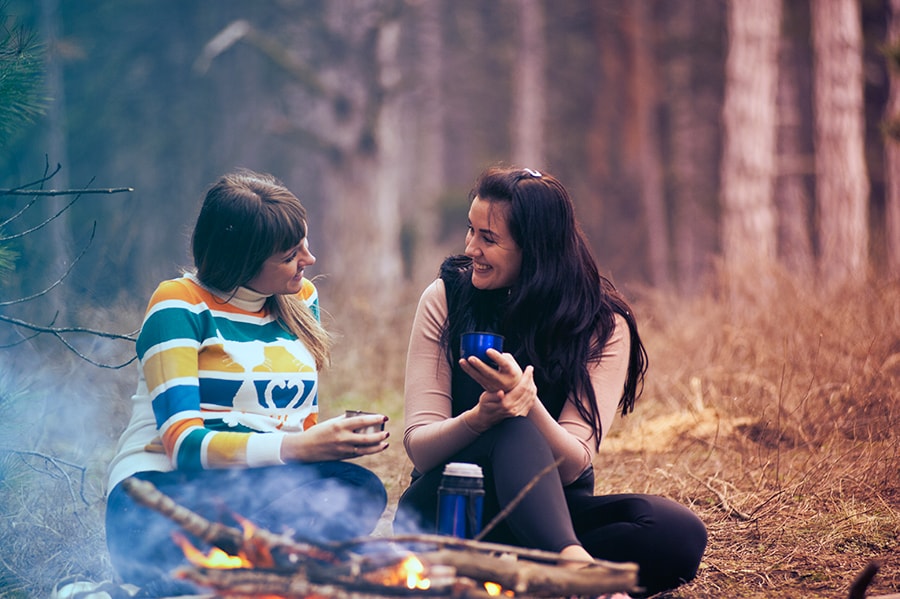 Two women talking around campfire